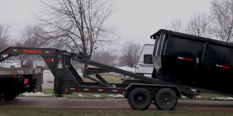 black roll off dumpster being delivered to driveway